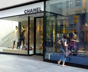 A imagem é de uma das ruas de Yorkville, um dos bairros mais luxuosos de Toronto. Na imagem tem a frente da loja da marca Chanel e tem uma mulher do lado direito olhando a vitrine da loja.