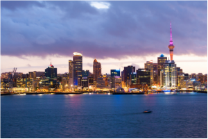 A imagem mostra um panorama da cidade de Auckland no entardecer. As luzes dos prédios já iluminam as ruas da cidade, refletindo levemente nas águas da Big Bay. Os arranha-céus são mera parte complementar da imagem, já que, no canto direito dela, se encontra a Sky Tower, colorida em rosa, chamando toda a atenção para si.