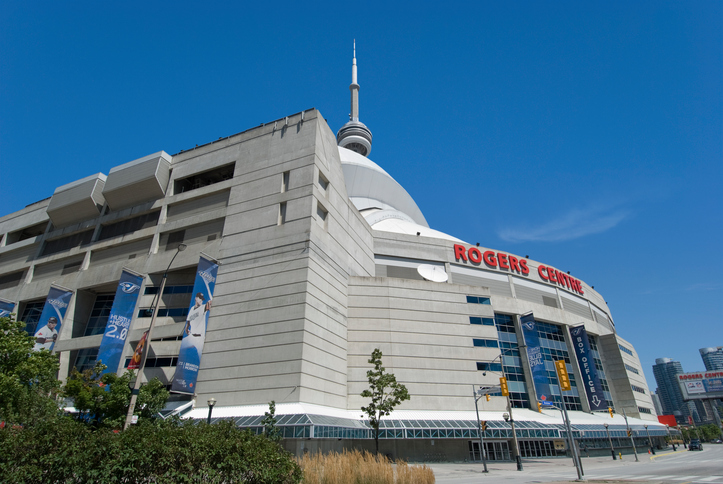 Fachada do estádio Rogers Centre. Uma estrutura na cor cinza com letras na cor vermelha escrito “Rogers Centre” na frente do prédio.