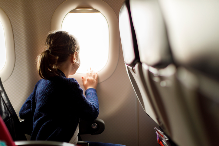 Menina olhando através da janela do avião