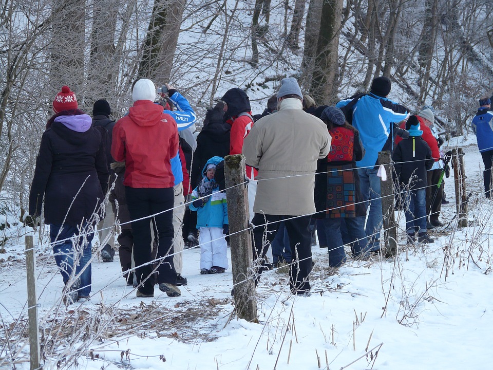 Pessoas caminhando na neve usando casacos apropriados para o clima